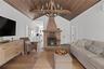 Living room with wood ceiling, a chandelier, high vaulted ceiling, wood finished floors, and a brick fireplace