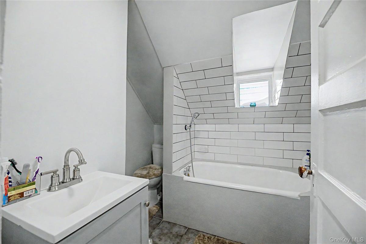 Bathroom featuring a white subway tile surround, built-in bathtub, and a vanity with a brushed nickel faucet