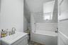 Bathroom featuring a white subway tile surround, built-in bathtub, and a vanity with a brushed nickel faucet