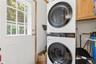 Dedicated laundry area featuring a stacked washer and dryer unit, wood-finish cabinetry, and a water filtration system