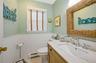 Half bathroom with vanity, toilet, a baseboard heating unit, and wainscoting