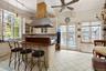 Kitchen featuring dark countertops, light tile patterned floors, backsplash, a kitchen island, and crown molding