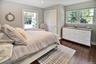 Bedroom featuring multiple windows, dark wood-style flooring, and a closet