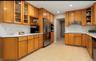 Kitchen featuring stainless steel appliances, tasteful backsplash, brown cabinets, under cabinet range hood, and light countertops