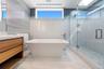 Bathroom with vanity, a soaking tub, a marble finish shower, tile walls, and light marble finish flooring