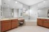 Primary bathroom features dual vanities with dressing area and a garden tub