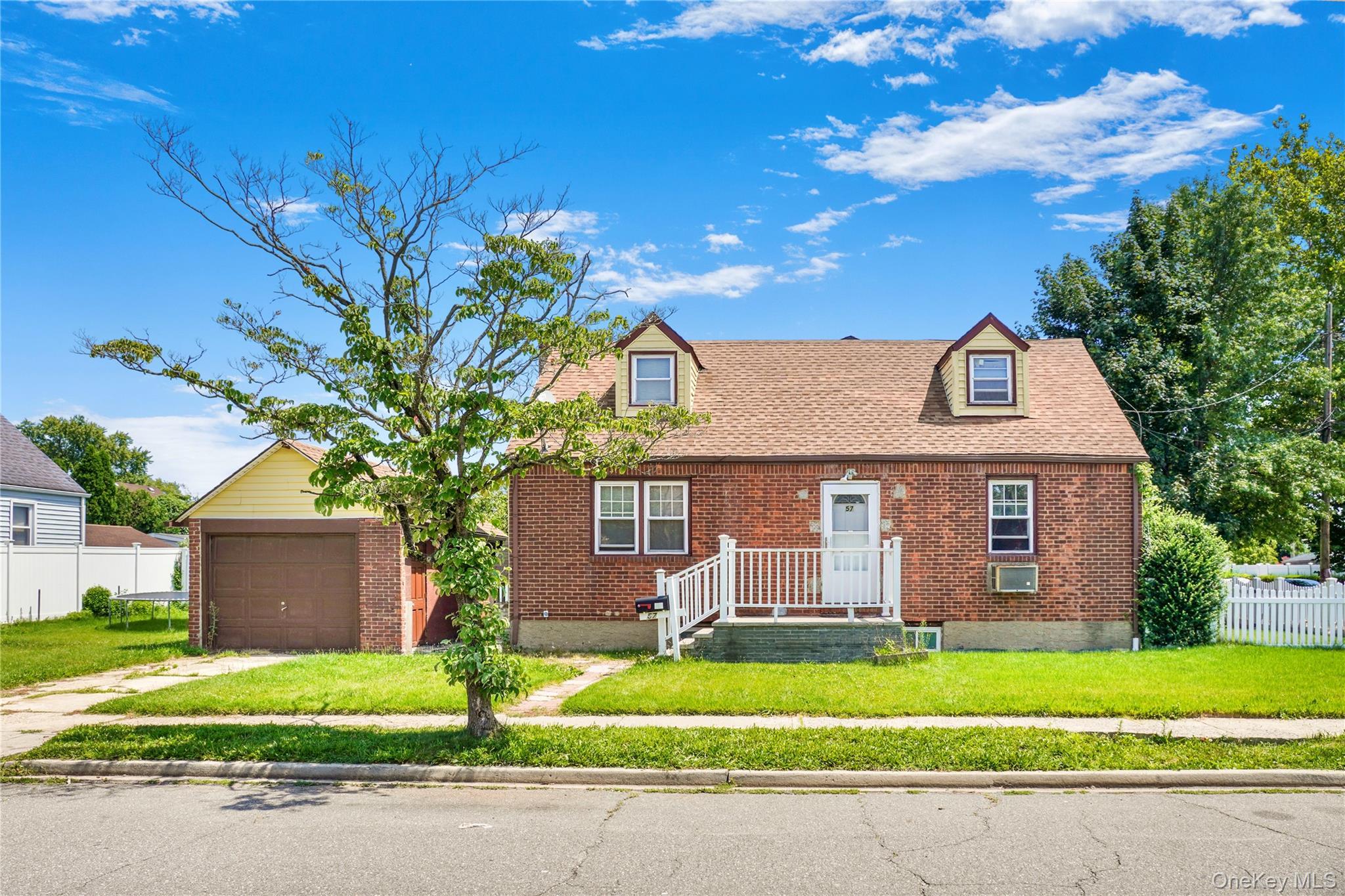 Brick facade home featuring a gabled roof and two dormer windows
