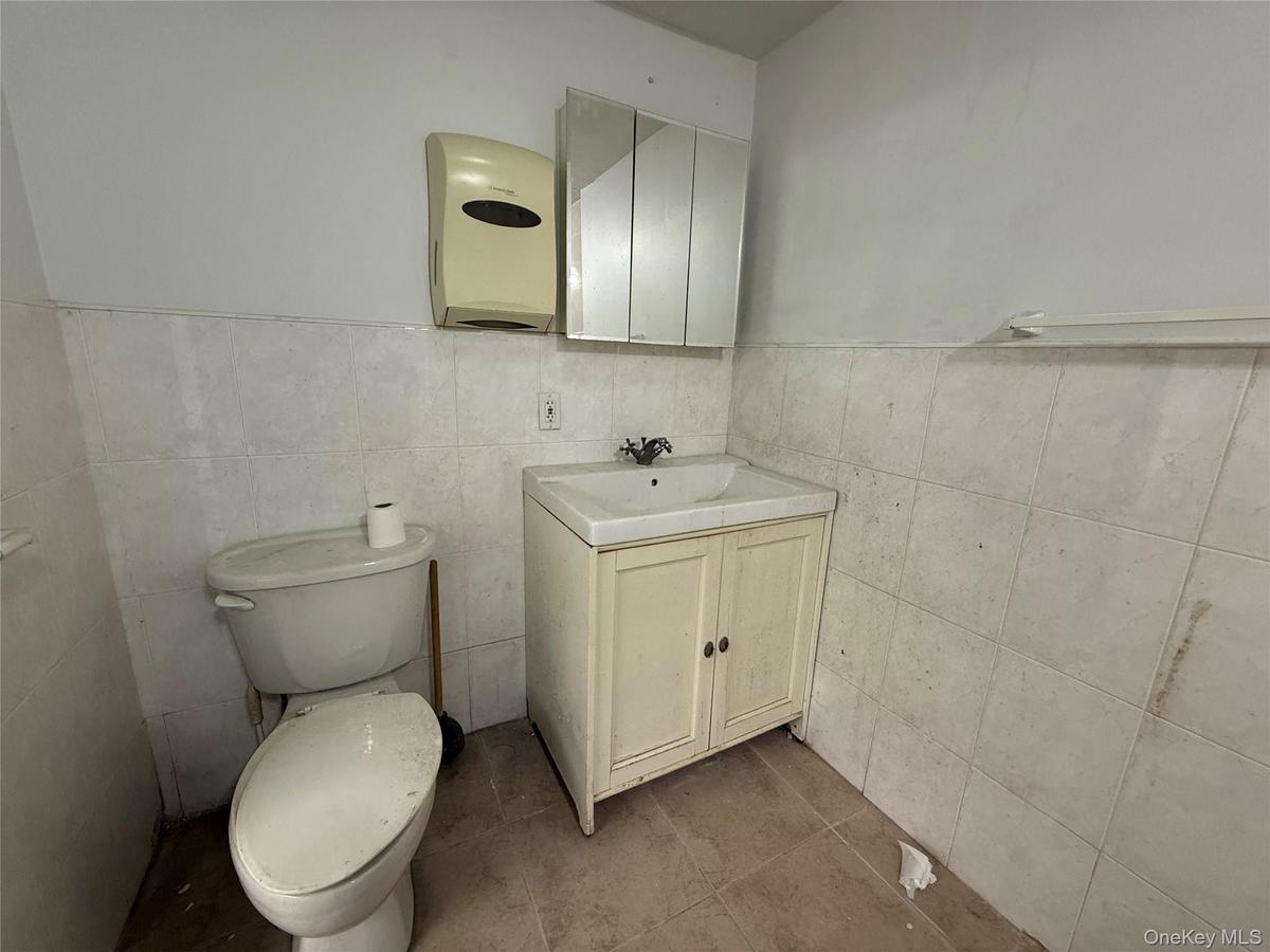 Bathroom with tile patterned flooring, vanity, toilet, and tile walls