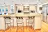 Kitchen featuring decorative light fixtures, cream cabinetry, premium appliances, recessed lighting, and light stone countertops. Subzero refrigerator