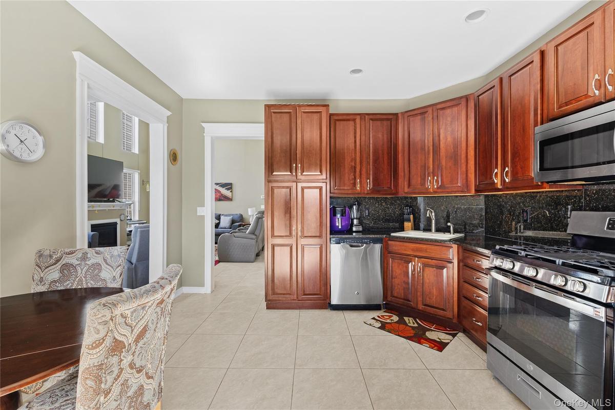 Kitchen featuring wood cabinetry, stainless steel appliances, dark stone countertops, and a tile floor