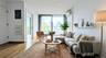 Living area with expansive windows, light wood finished floors, a wall mounted AC, and electric panel