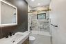 Contemporary bathroom featuring a vanity with integrated sink, matte black fixtures, and an illuminated mirror