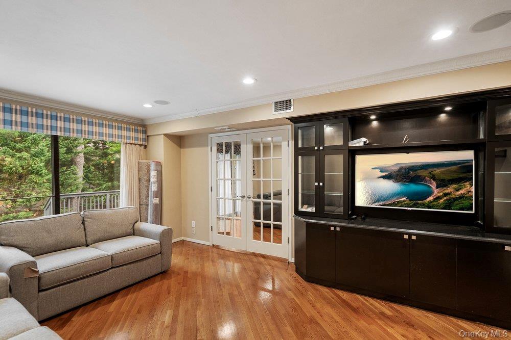 Wood-finish flooring throughout, featuring a large built-in media cabinet with display shelving and accent lighting