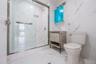 Bathroom featuring a marble finish shower, vanity, marble tiled floors, and stone wall
