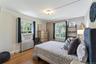 Bedroom with radiator, multiple windows, wood finished floors, and ornamental molding