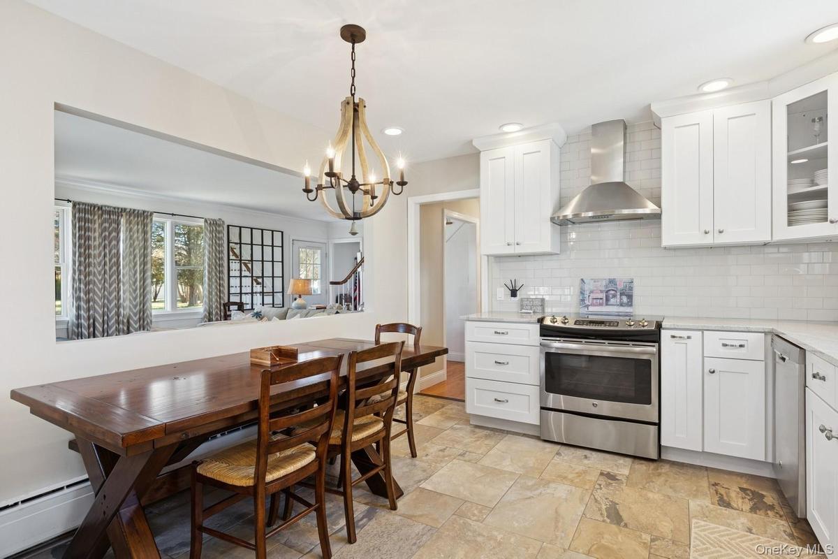 Kitchen featuring stainless steel appliances, wall chimney exhaust hood, white cabinetry, glass insert cabinets, and recessed lighting