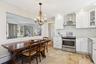 Kitchen featuring stainless steel appliances, wall chimney exhaust hood, white cabinetry, glass insert cabinets, and recessed lighting