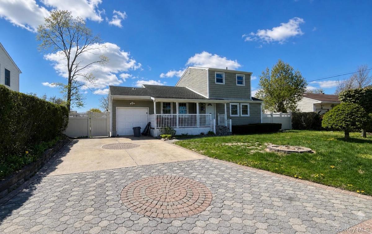 Two-story residence featuring light green siding and white trim with beautiful driveway