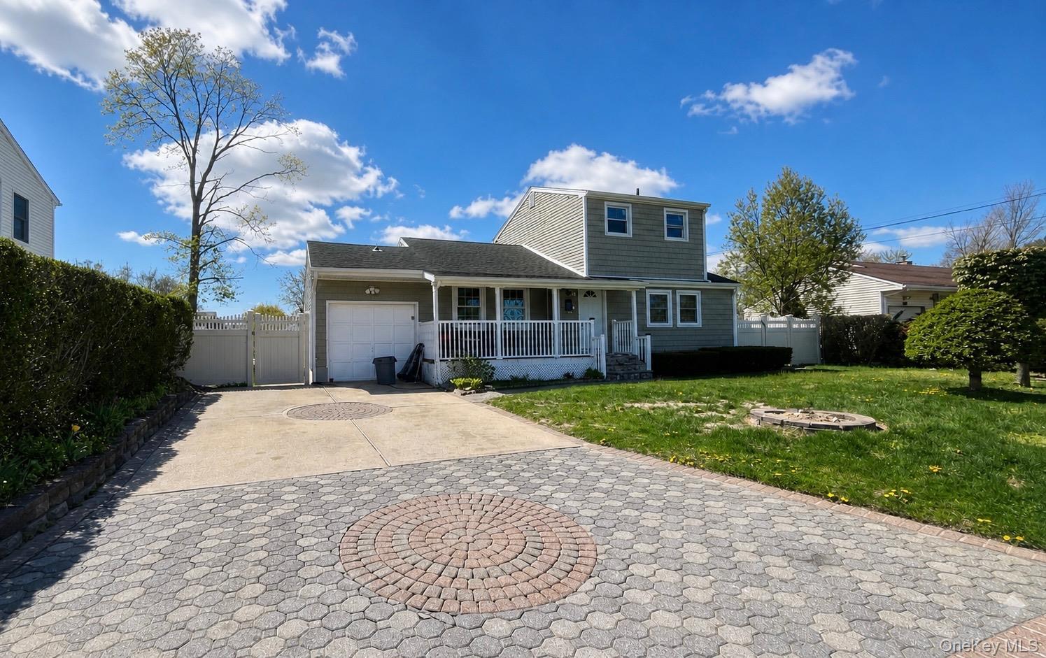 Two-story residence featuring light green siding and white trim with beautiful driveway