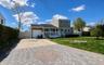 Two-story residence featuring light green siding and white trim with beautiful driveway