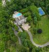 Expansive estate featuring a large swimming pool, paved patio areas, and a full-size tennis court