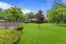 Expansive green lawn with mature trees and perimeter landscaping