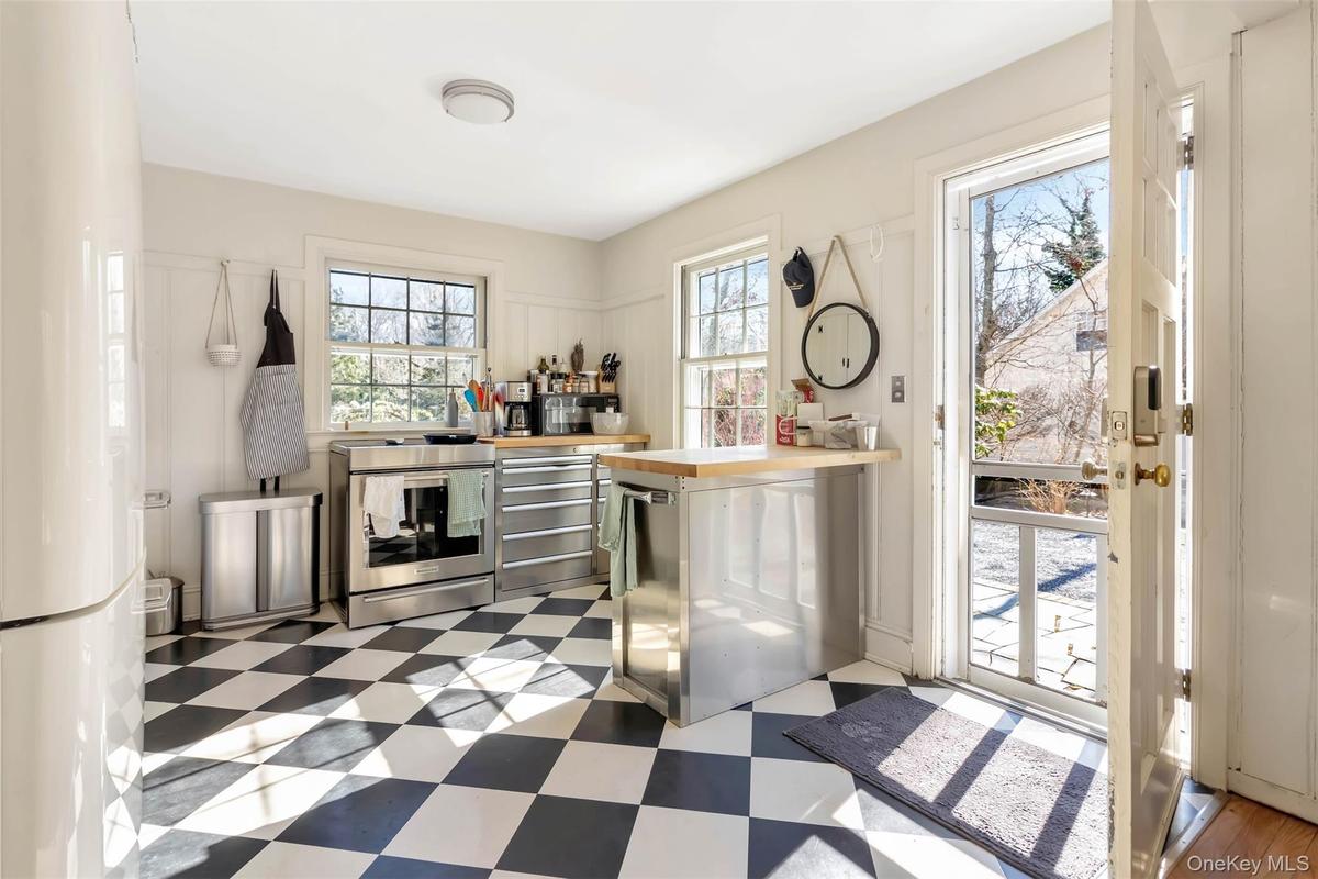 Bar with refrigerator, dishwashing machine, stainless steel range with electric stovetop, and tile patterned floors