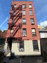 Red brick exterior facade featuring multiple windows and a multi-level fire escape system