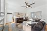 Living area with a ceiling fan, vaulted ceiling, baseboards, and light wood-style flooring