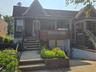 View of front of house featuring covered porch, brick siding, and stairs