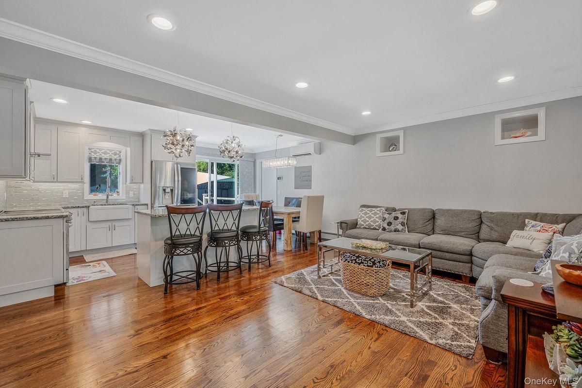 Living room featuring ornamental molding, light wood-style floors, recessed lighting, a chandelier, and a wall mounted air conditioner