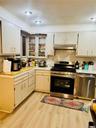 Kitchen featuring appliances with stainless steel finishes, light countertops, light wood-style floors, under cabinet range hood, and decorative backs