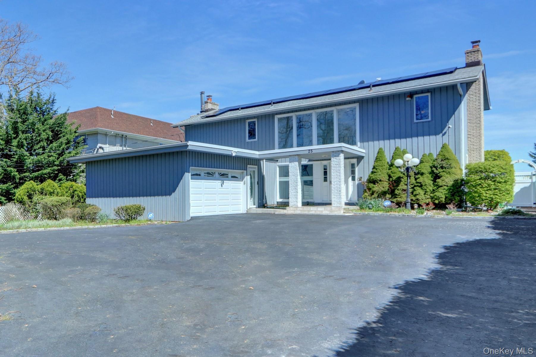 View of front of home with a chimney, solar panels, asphalt driveway, and an attached garage