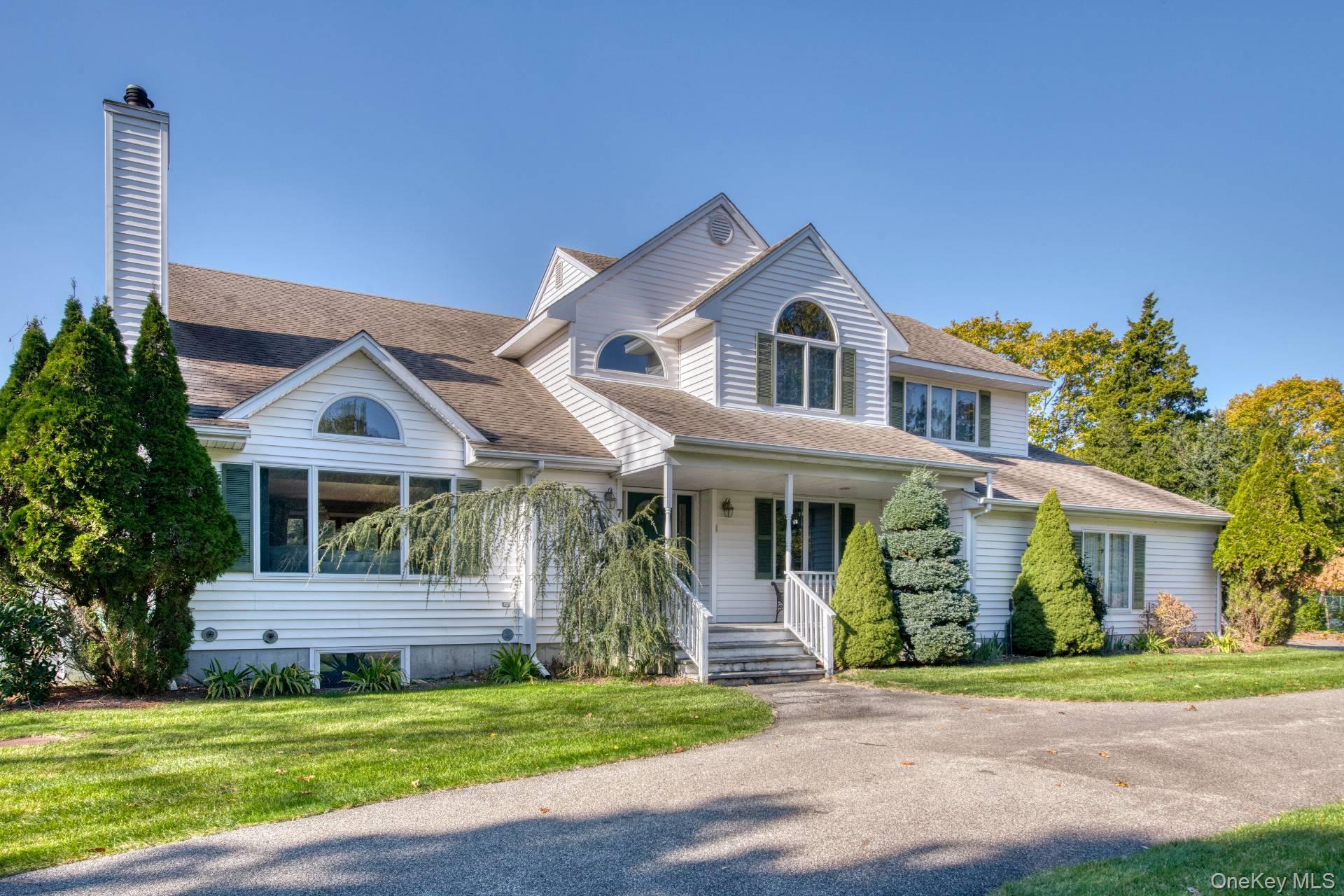 Traditional home featuring a shingled roof, a chimney, and a front lawn