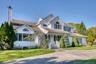 Traditional home featuring a shingled roof, a chimney, and a front lawn