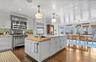 Kitchen with high end appliances, wall chimney range hood, a kitchen island, wood counters, and dark wood-style floors
