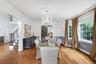 Hardwood flooring, chandelier with ceiling medallion, decorative wall sconces, columned archway, and wrought iron stair railing