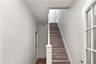 Staircase featuring wood-finish treads and white risers, framed by a white newel post and handrail
