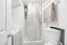 Shower with white subway tile surround, white shower pan, white vanity with integrated sink, and white toilet