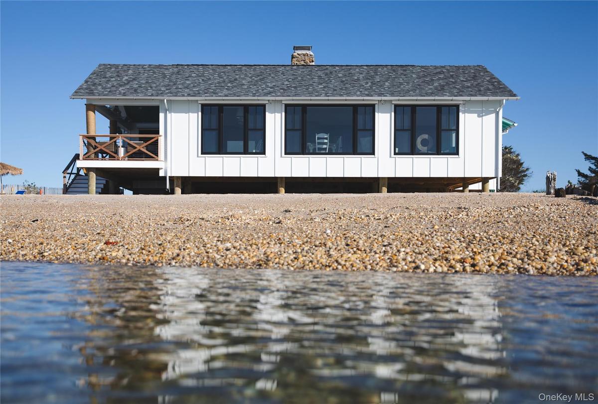 View of front of home featuring a water view, board and batten siding, a chimney, and roof with shingles