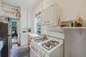 Kitchen with white cabinets, white gas stove, open shelves, a textured ceiling, and freestanding refrigerator