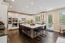 Kitchen featuring tasteful backsplash, light stone counters, a breakfast bar, an island with sink, and white cabinets