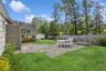 Fenced backyard featuring a patio area, a storage unit, a sunroom, and view of scattered trees