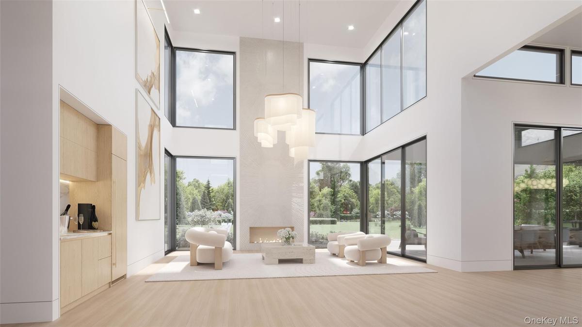 The great room blends refined interiors with the surrounding landscape; anchored by a sleek linear fireplace and complemented by a built-in bar with w