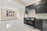 Recessed ceiling lighting, wood-framed window, sleek dark cabinetry, stainless steel range, and tile backsplash