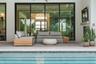 TThe expansive outdoor living area features a cozy fireplace, mounted television, and oversized lounge seating.