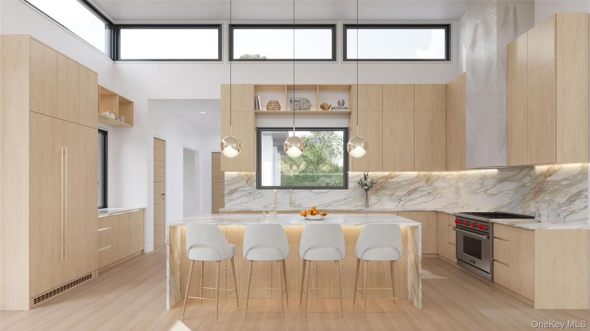 A sculptural waterfall marble island defines the kitchen, illuminated by warm brass pendants and framed by seamless indoor–outdoor flow.