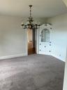 Empty room featuring arched walkways, carpet, and a chandelier
