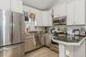 Kitchen with stainless steel appliances, white cabinetry, backsplash, lofted ceiling, and a sink