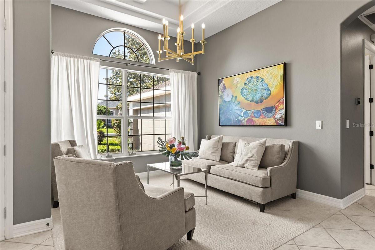 Formal living room has coffered ceilings and updated chandelier